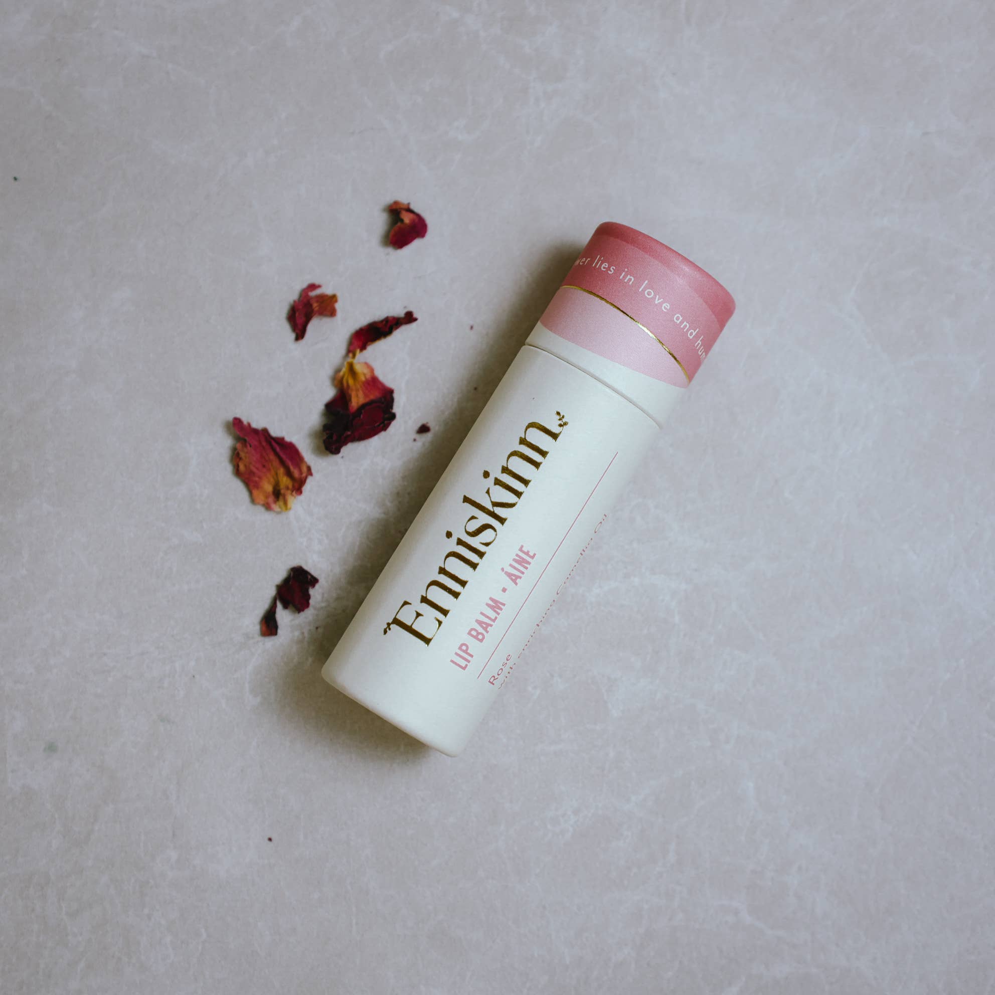 Lip balm with pink cap and visible brand name.