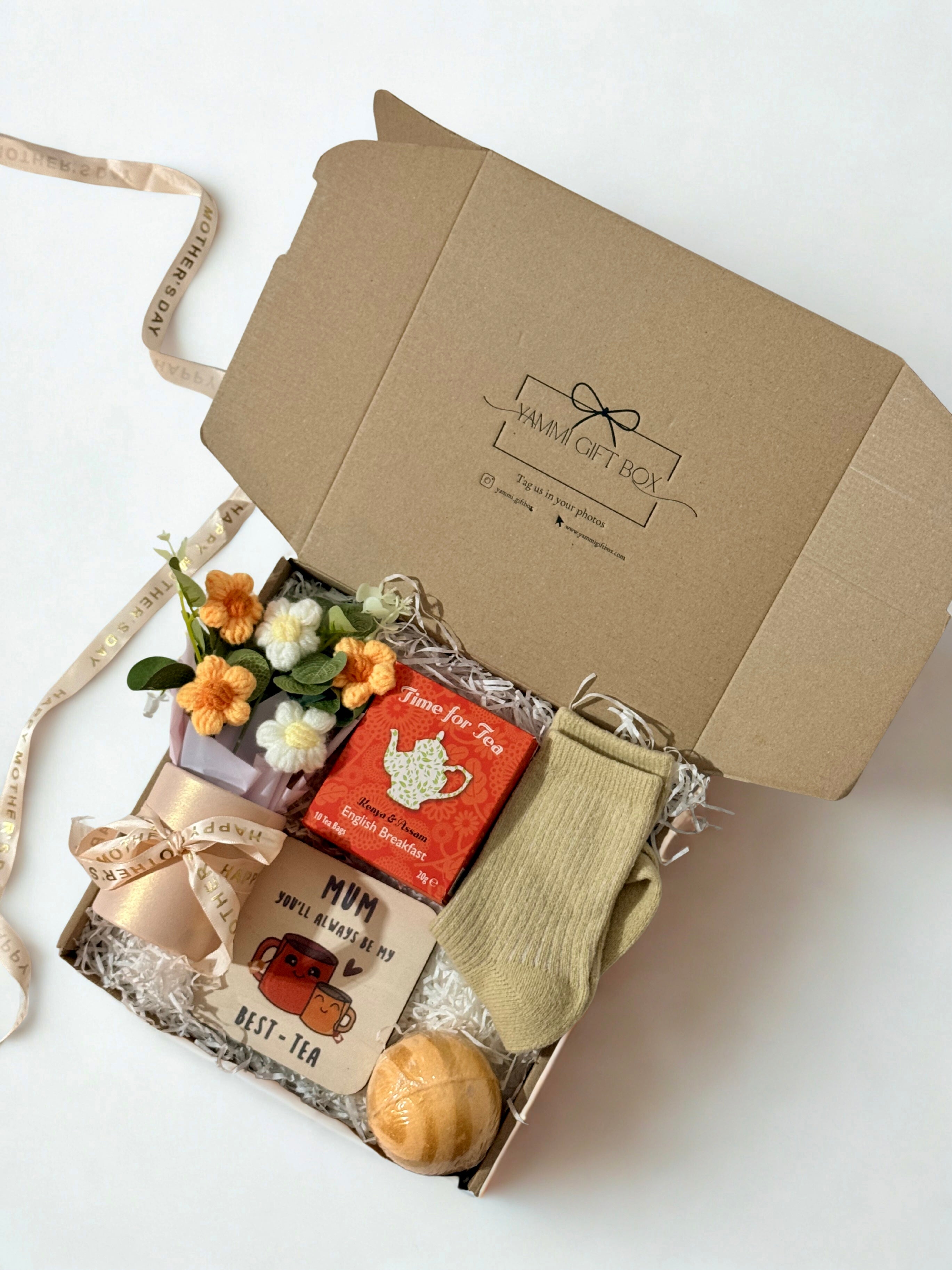Gift box with flowers, tea set, and socks on a white background