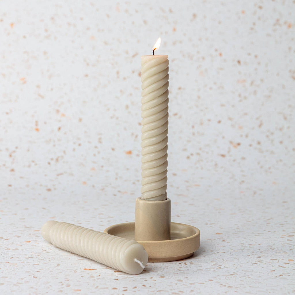 Beige candle holder with a twisted candle.