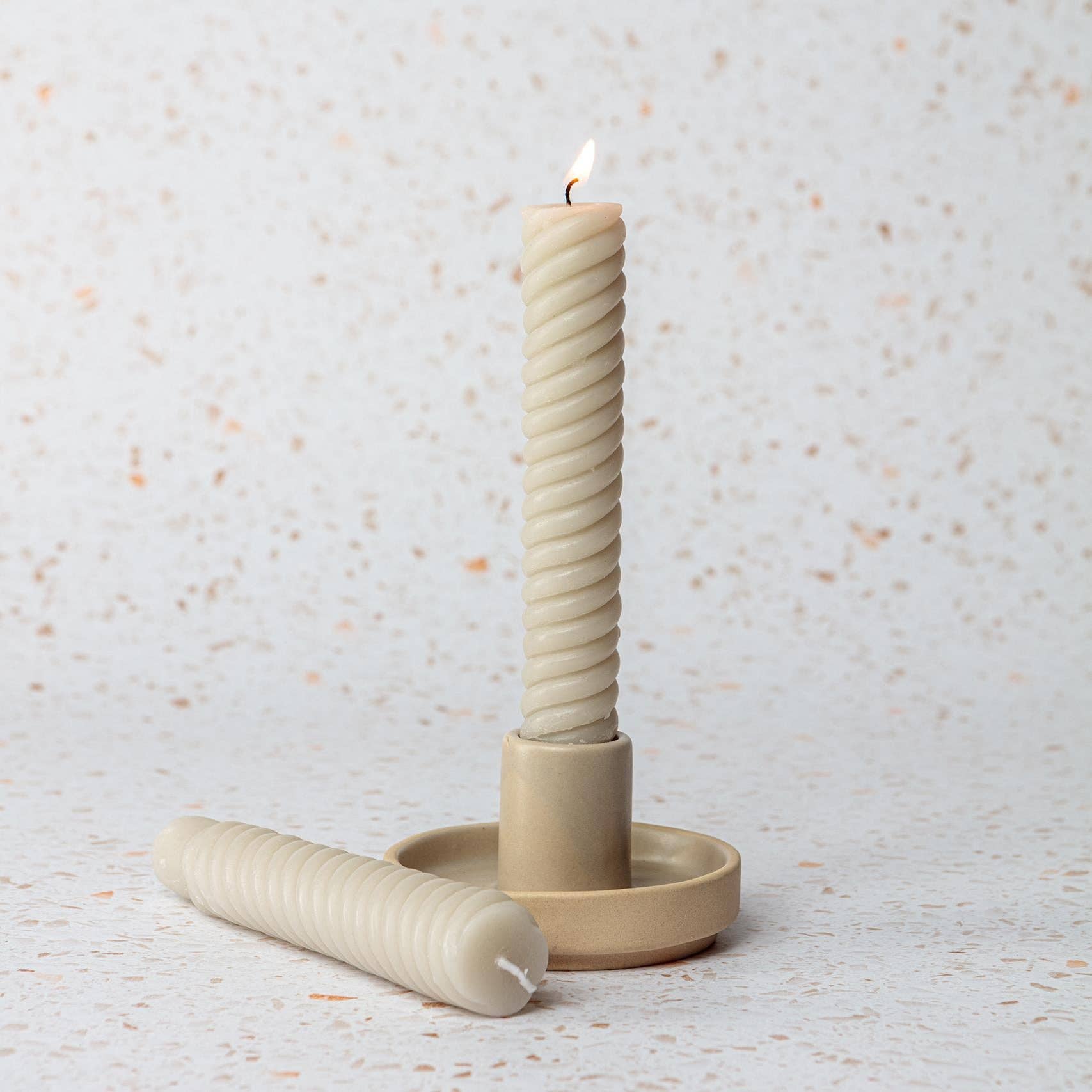 Beige candle holder with a twisted candle.