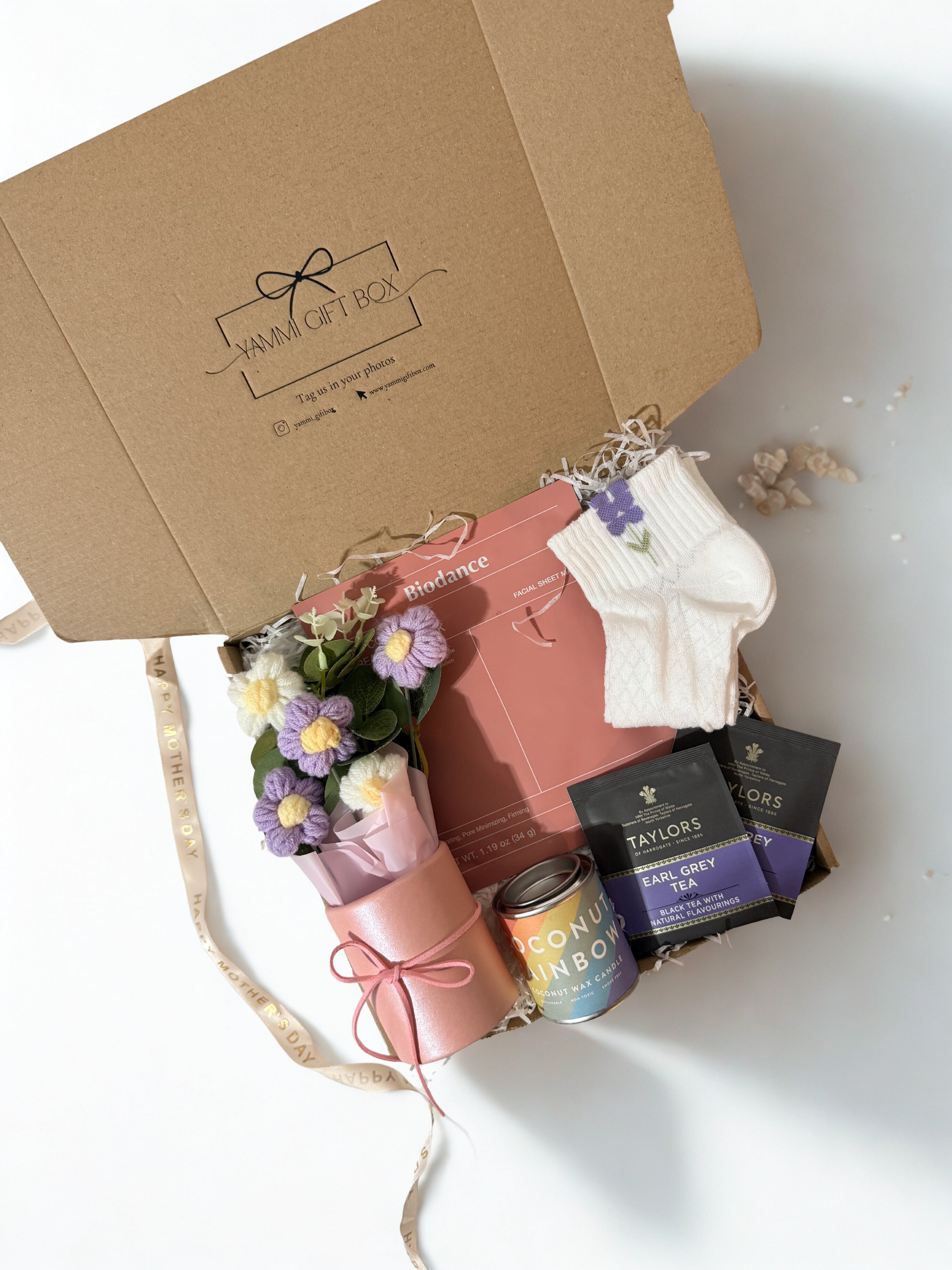 Gift set with flowers, books, and tea boxes on a white surface