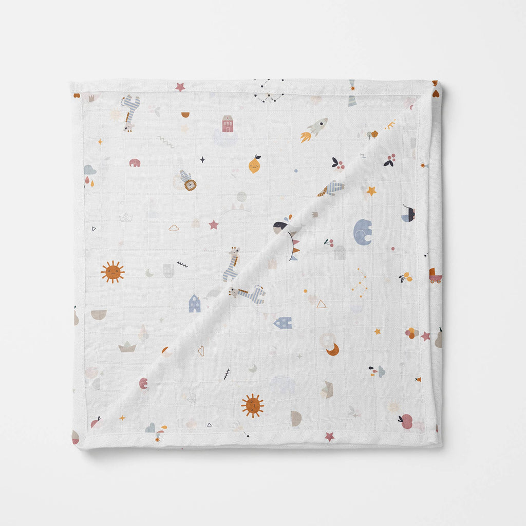 Soft white organic muslin swaddle blanket with playful outer space-themed print, featuring suns, rockets, planets, astronauts, stars, and whimsical icons.