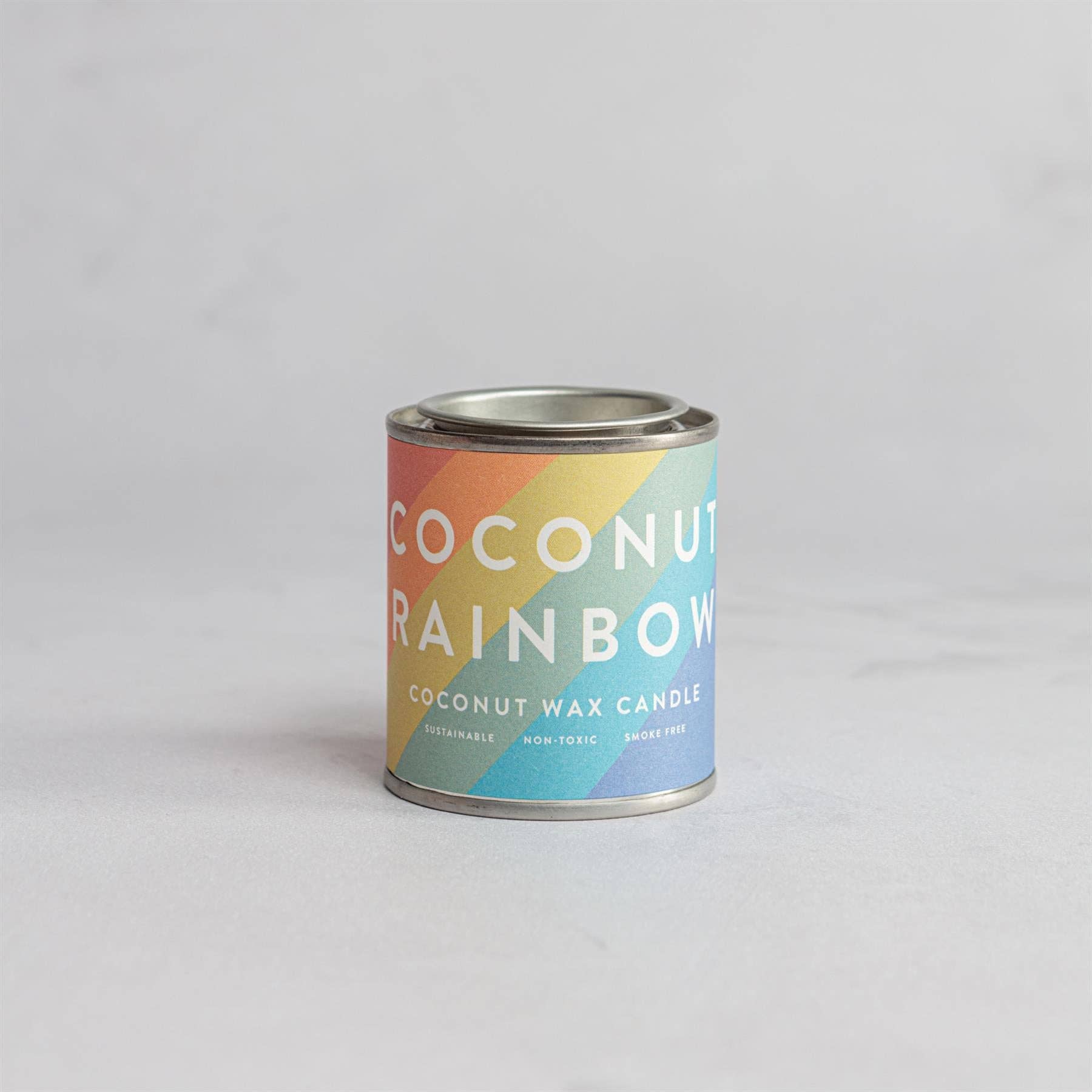 Coconut Rainbow candle in a tin with a colorful label.