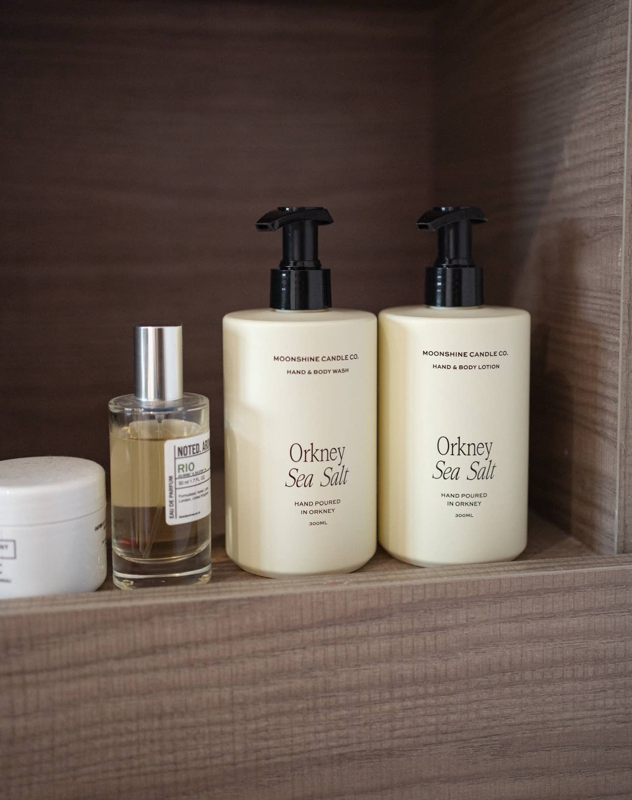 Three skincare products on a wooden shelf.