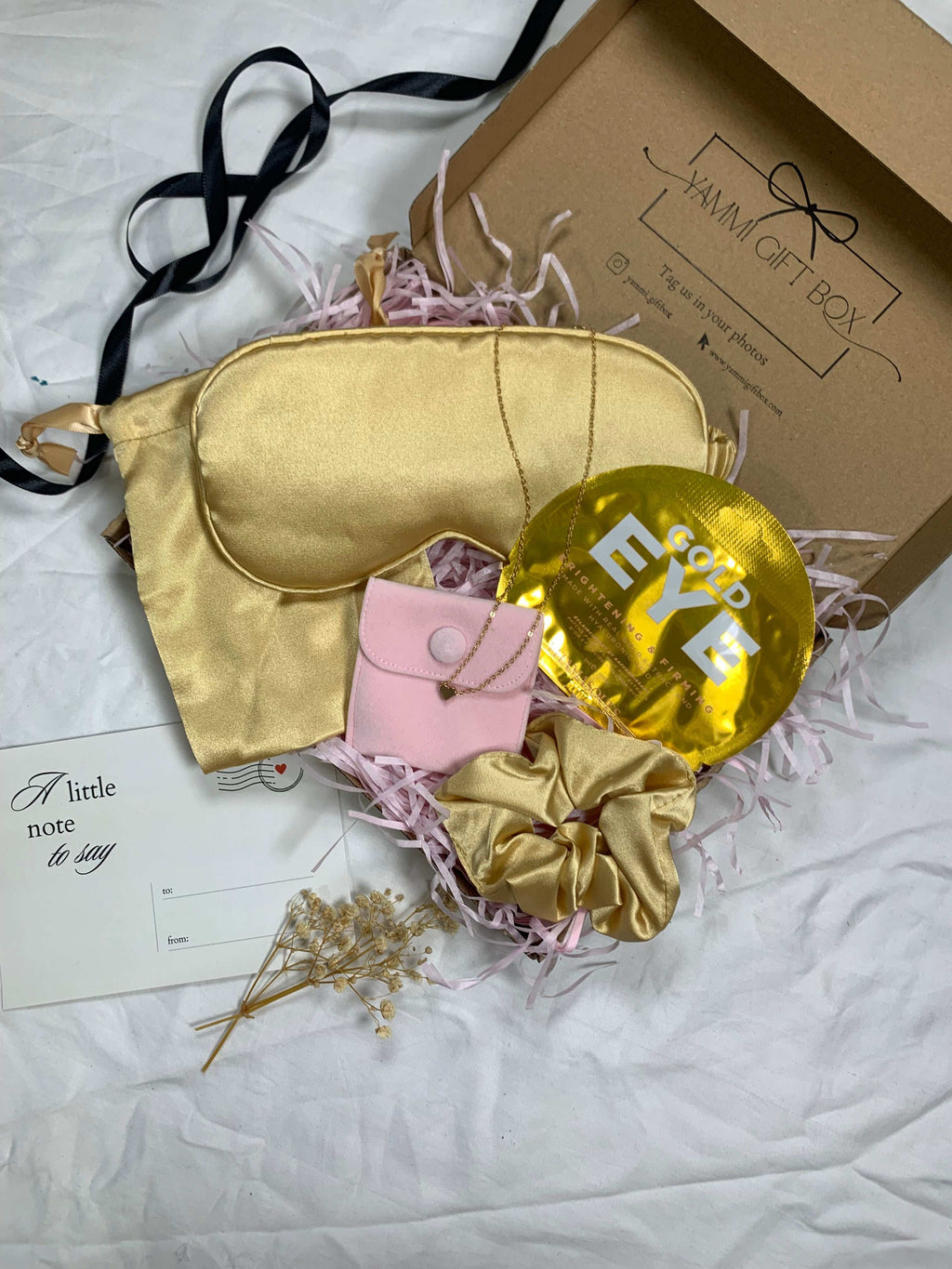 Gold sleep mask, gold balloon, pink pouch, and gold scrunchie.
