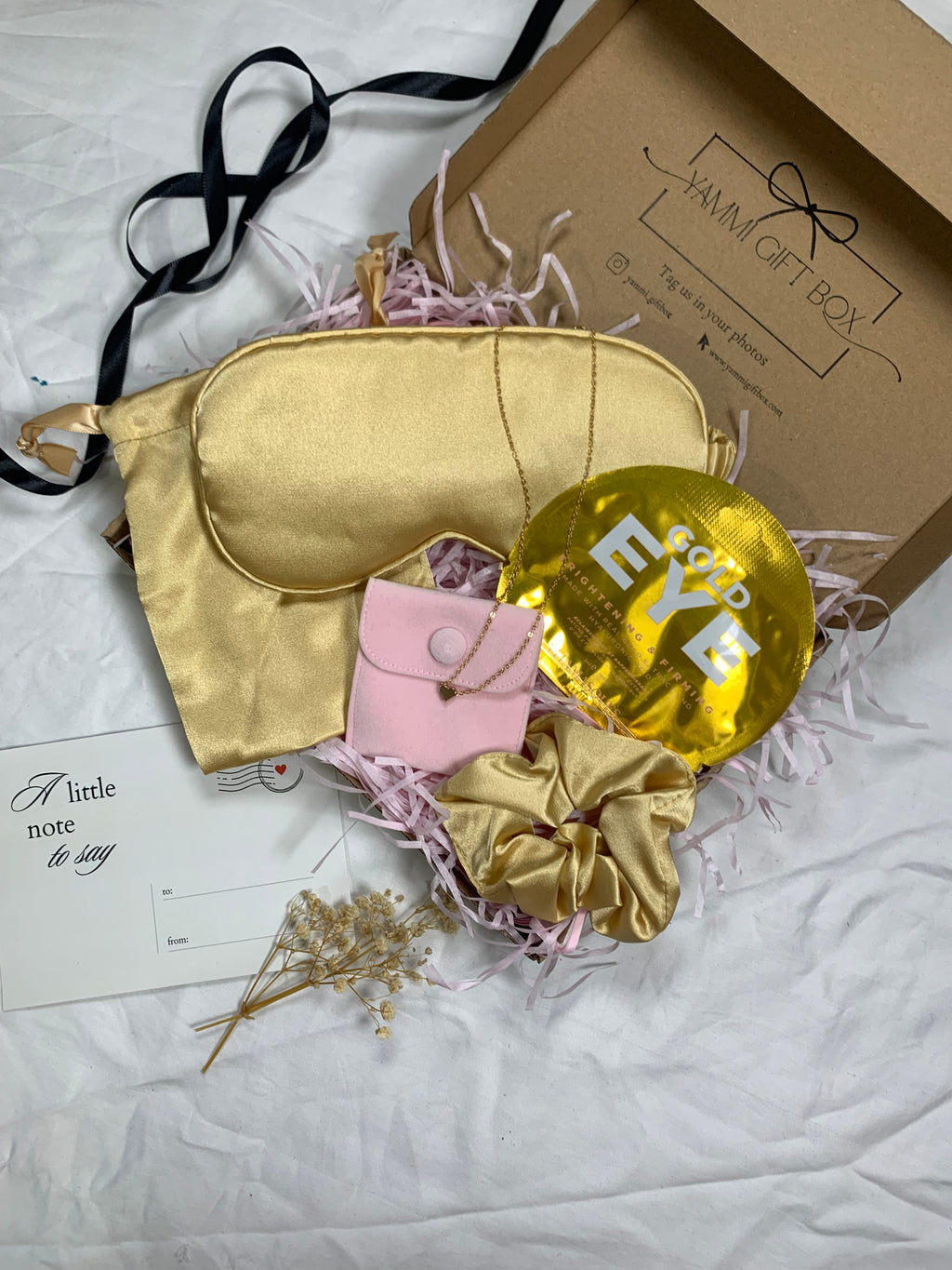Gold sleep mask, gold balloon, pink pouch, and gold scrunchie.