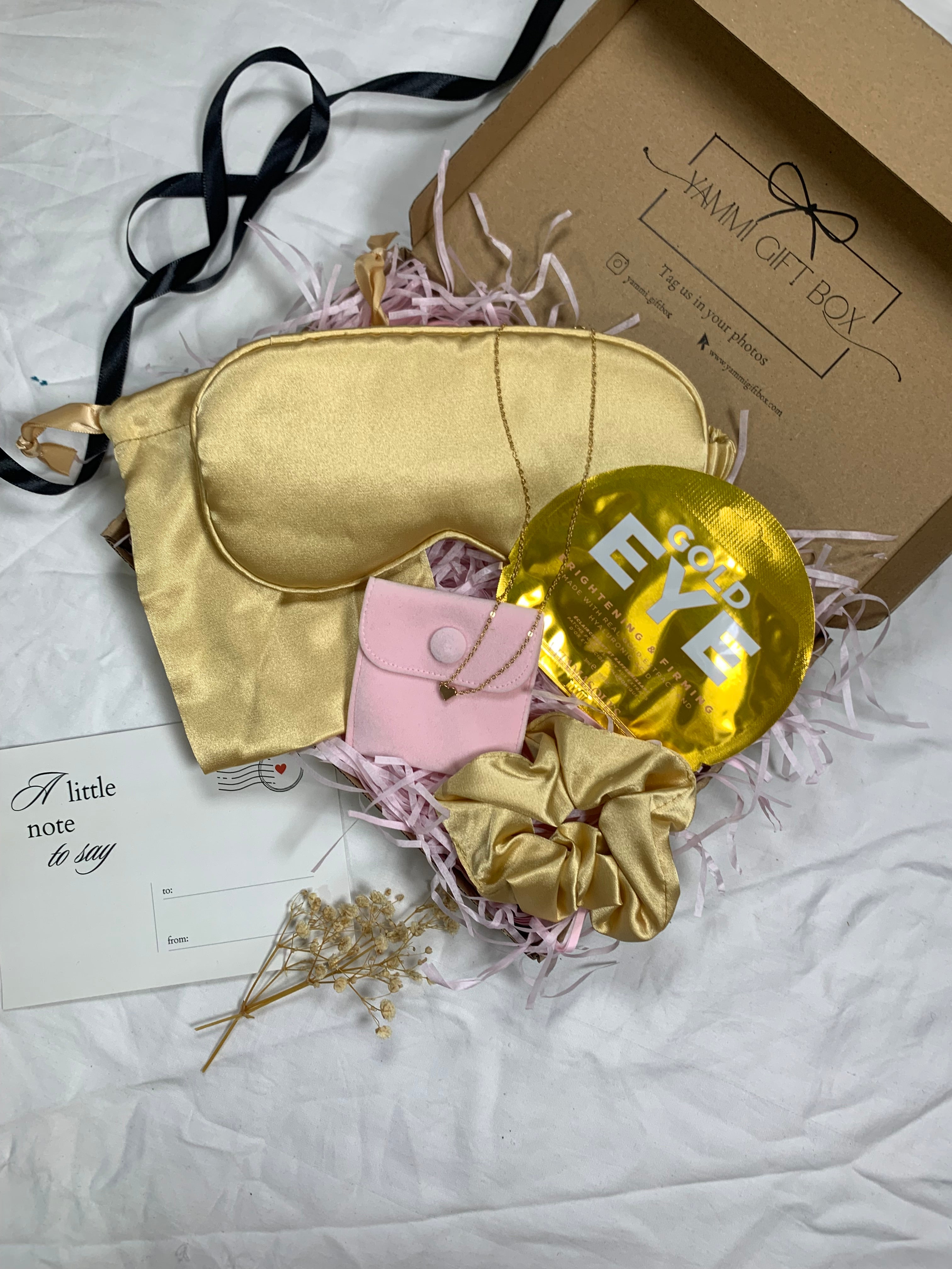 Gold sleep mask, gold balloon, pink pouch, and gold scrunchie.