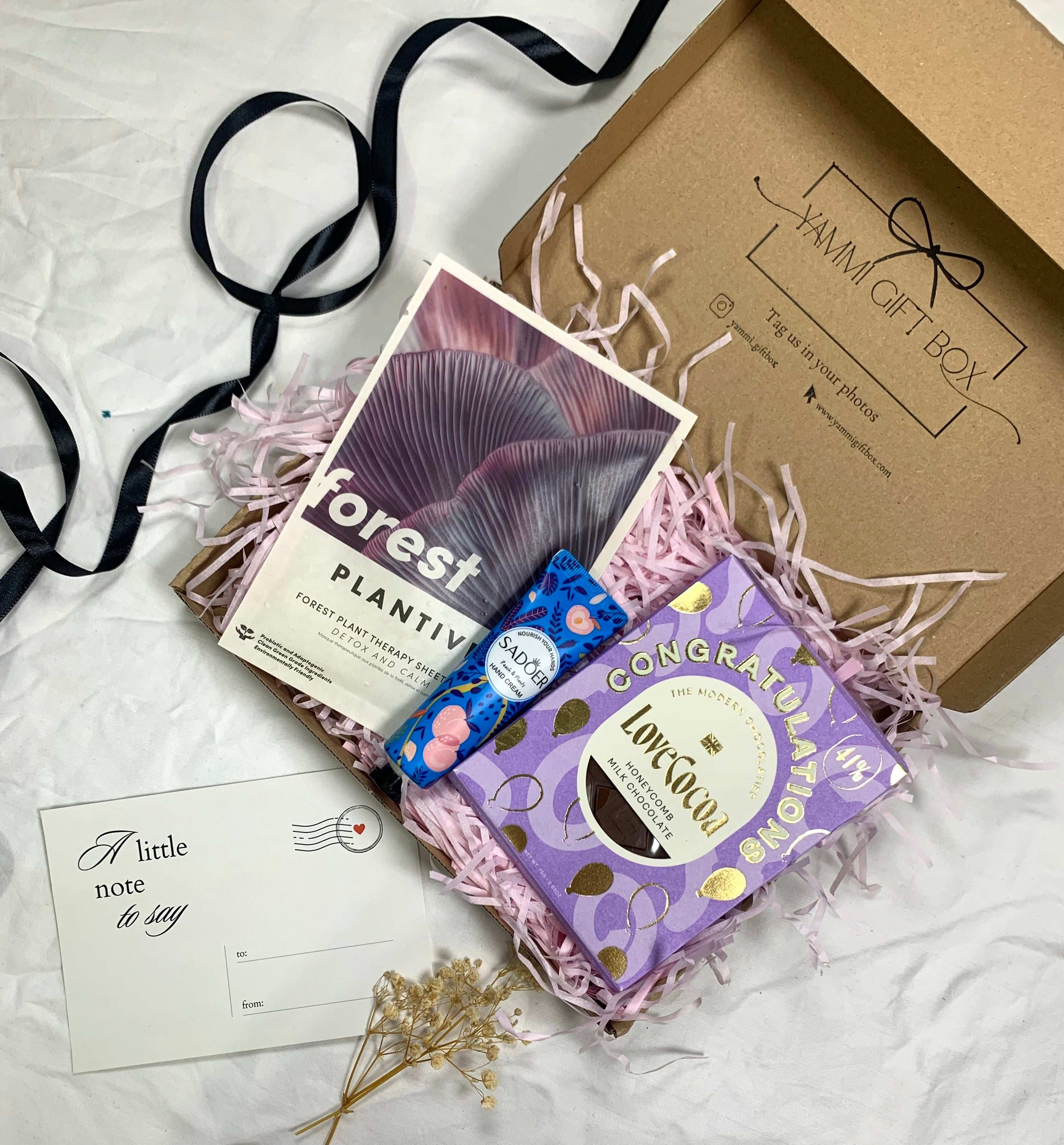 Thoughtful congratulations gift box featuring a purple “Congratulations” Love Cocoa chocolate bar, artisan blueberry white chocolate, a Forest-themed Plantiva soap bar, and a mini note card. A perfect celebration hamper for her or him.