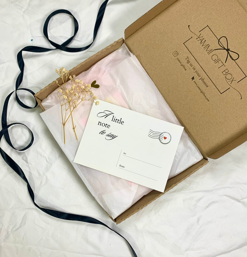 Eco-friendly Yammi Gift Box with a note card that reads “A little note to say,” decorated with dried flowers and pink tissue wrapping.