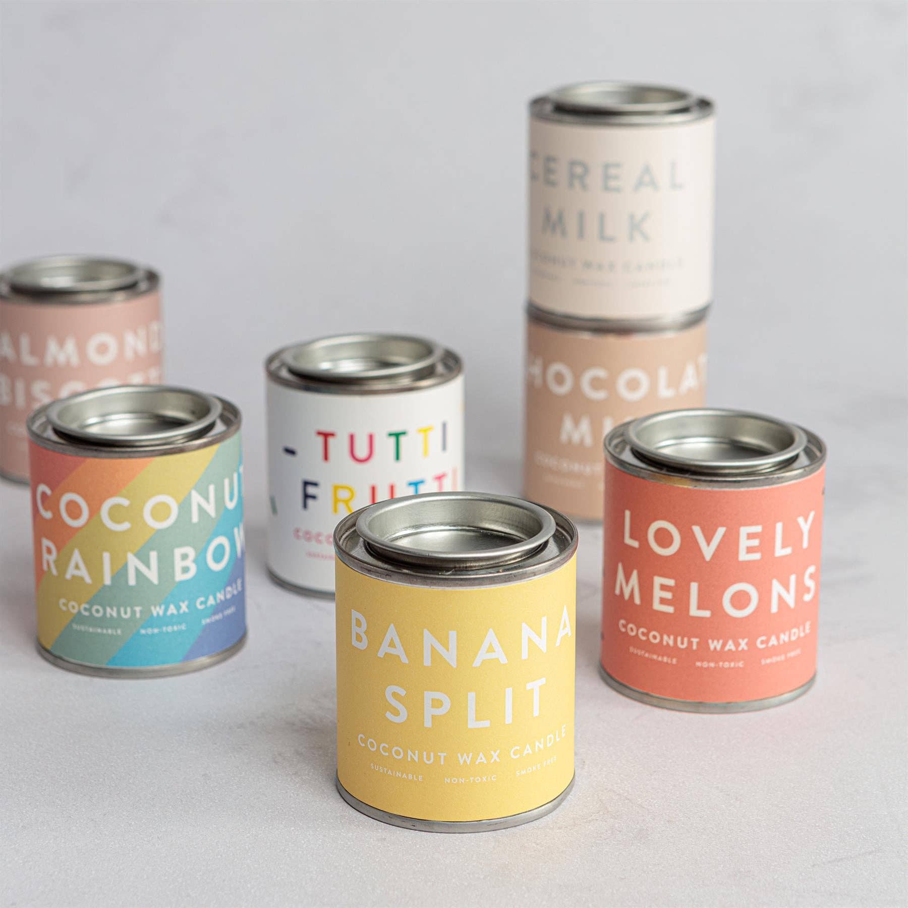 Set of colorful candle tins with various flavors.