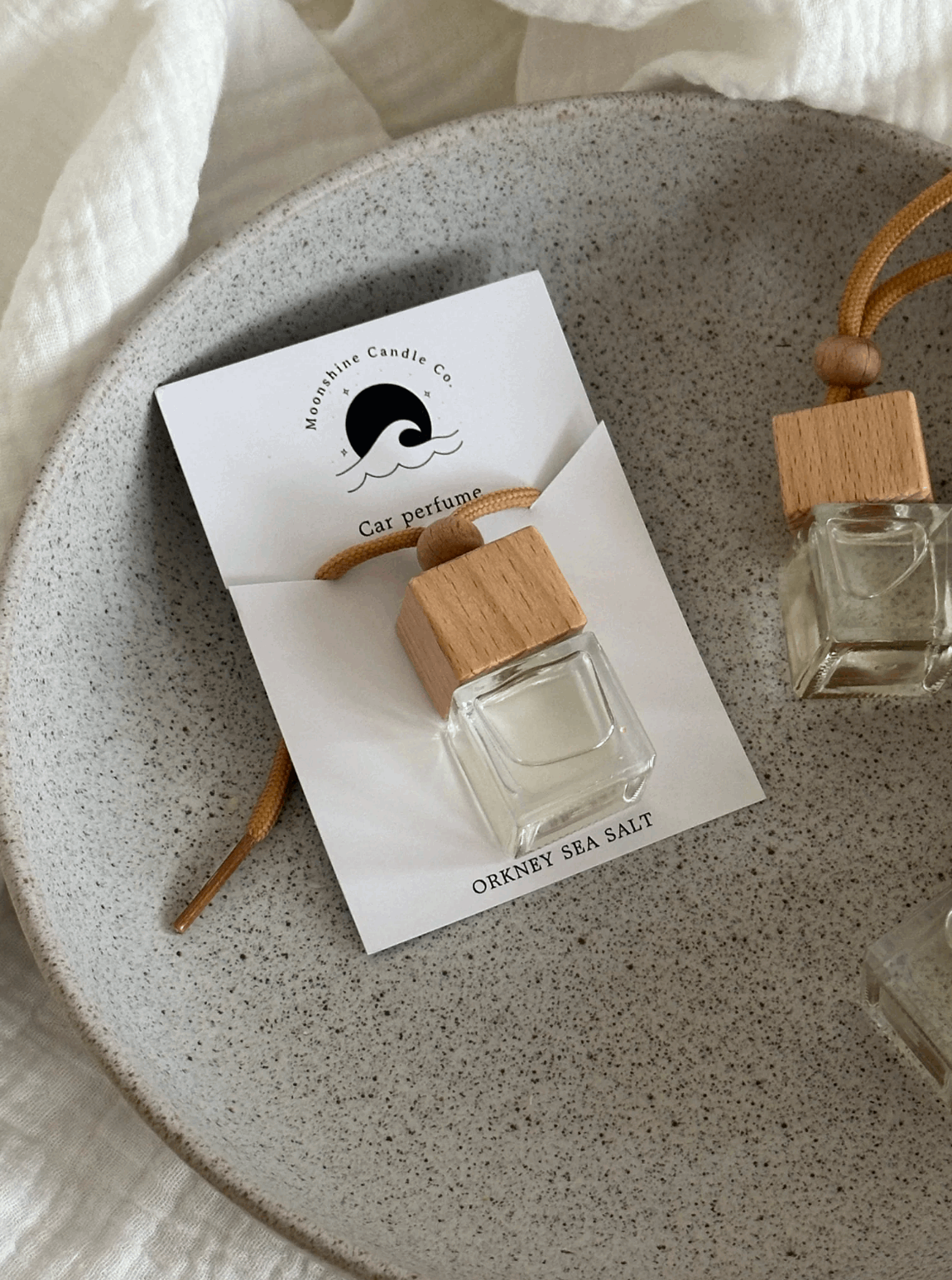 Car perfume bottle with wooden cap on a branded card.