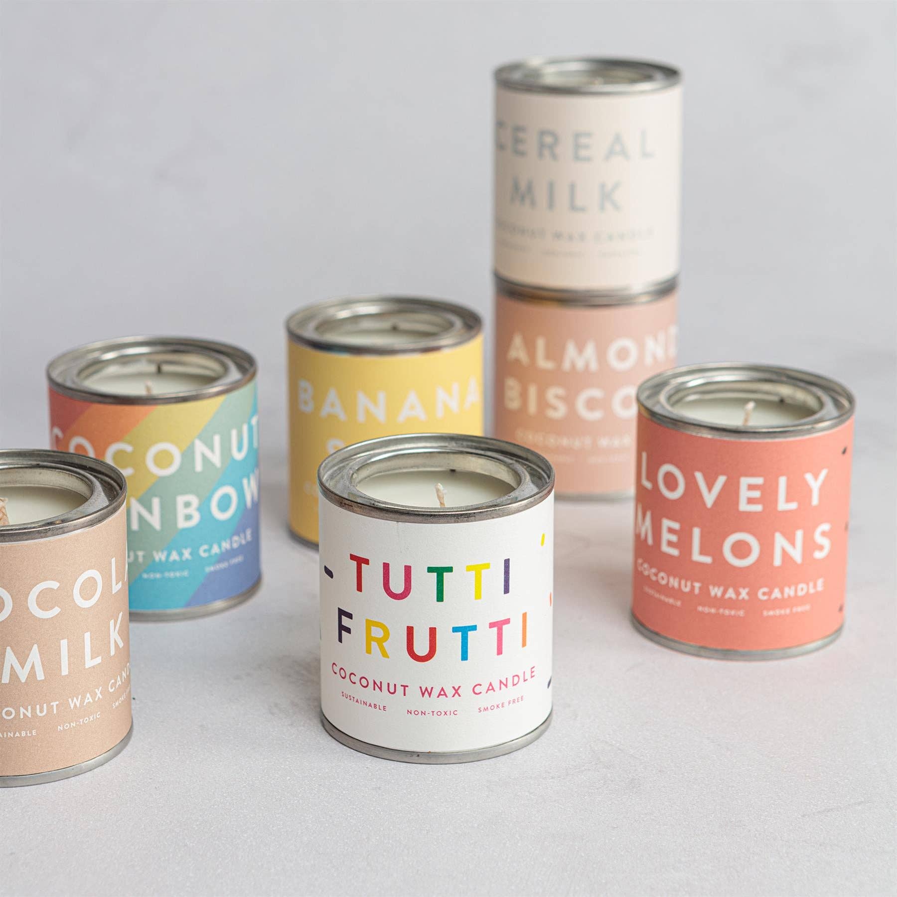 Set of coconut wax candles in tin canisters with colorful labels.